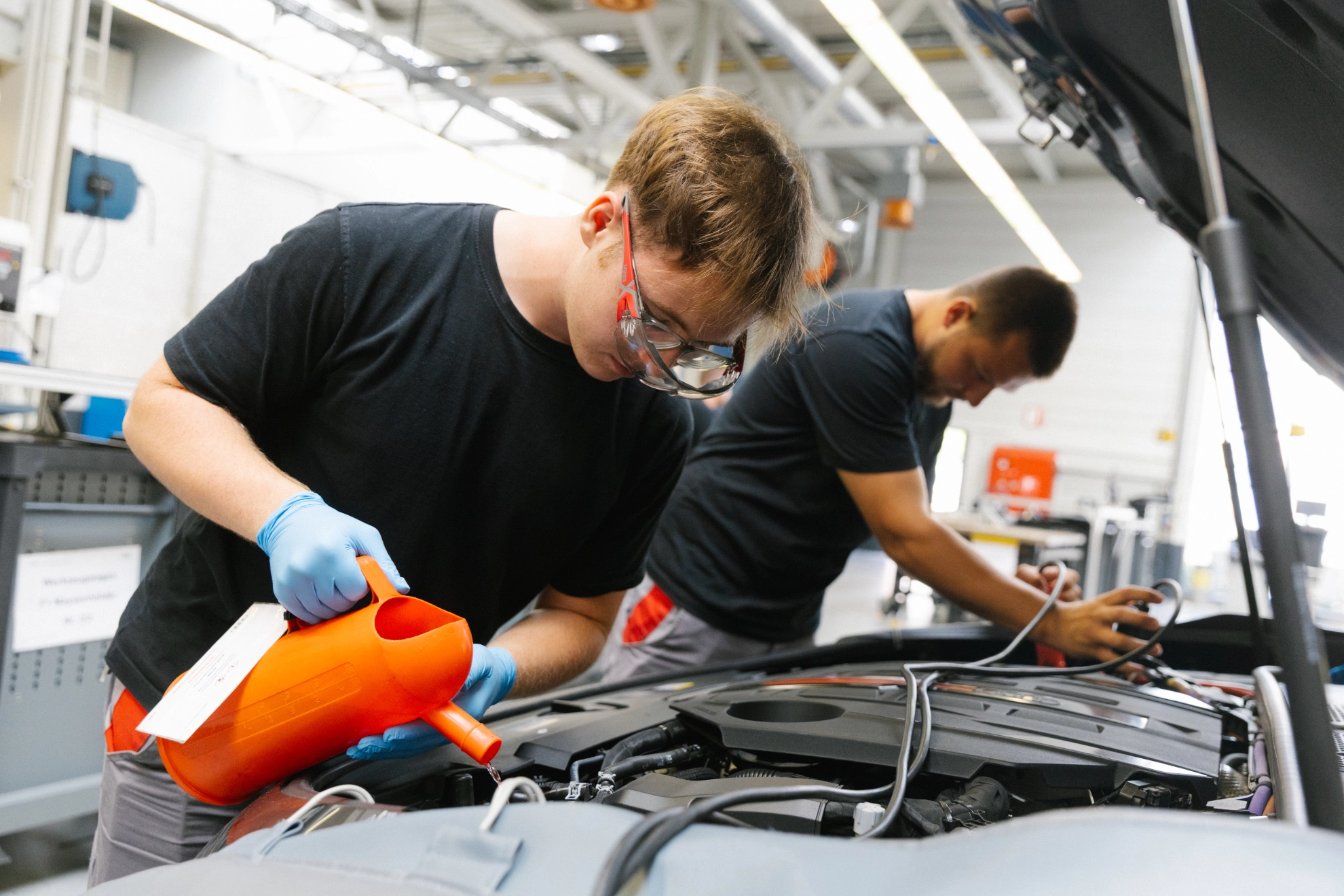 Zwei Auszubildende bei Audi in Neckarsulm füllen das Scheibenwischwasser nach.