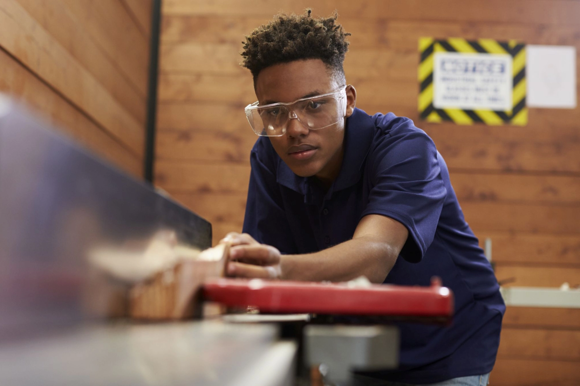 Junger Mann arbeitet in einer Werkstatt mit Holz