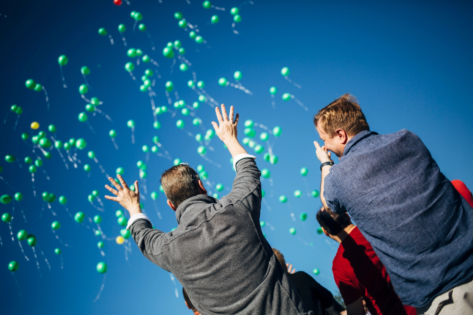 Zwei Menschen mit grünen Luftballons_Symbolbild
